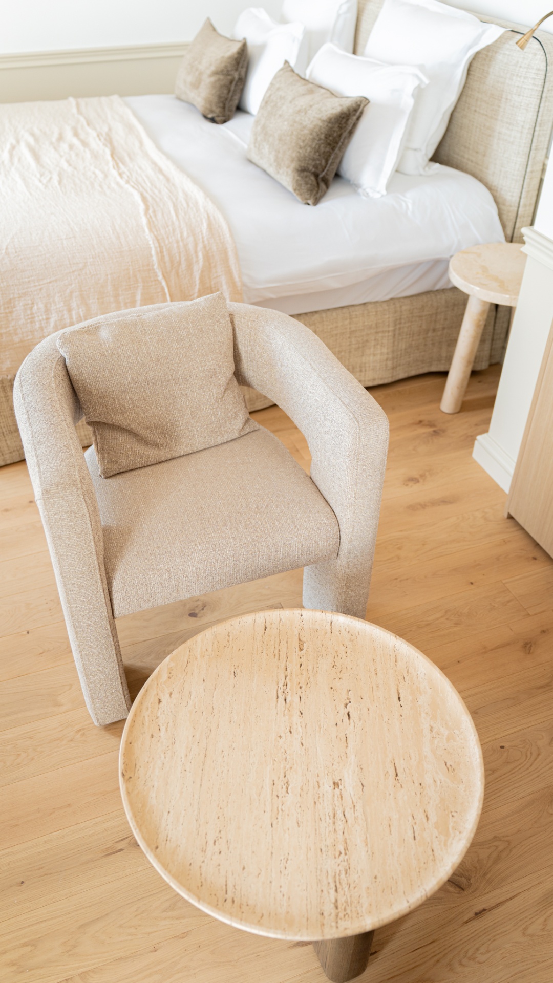 Fauteuil beige et table travertin dans la chambre