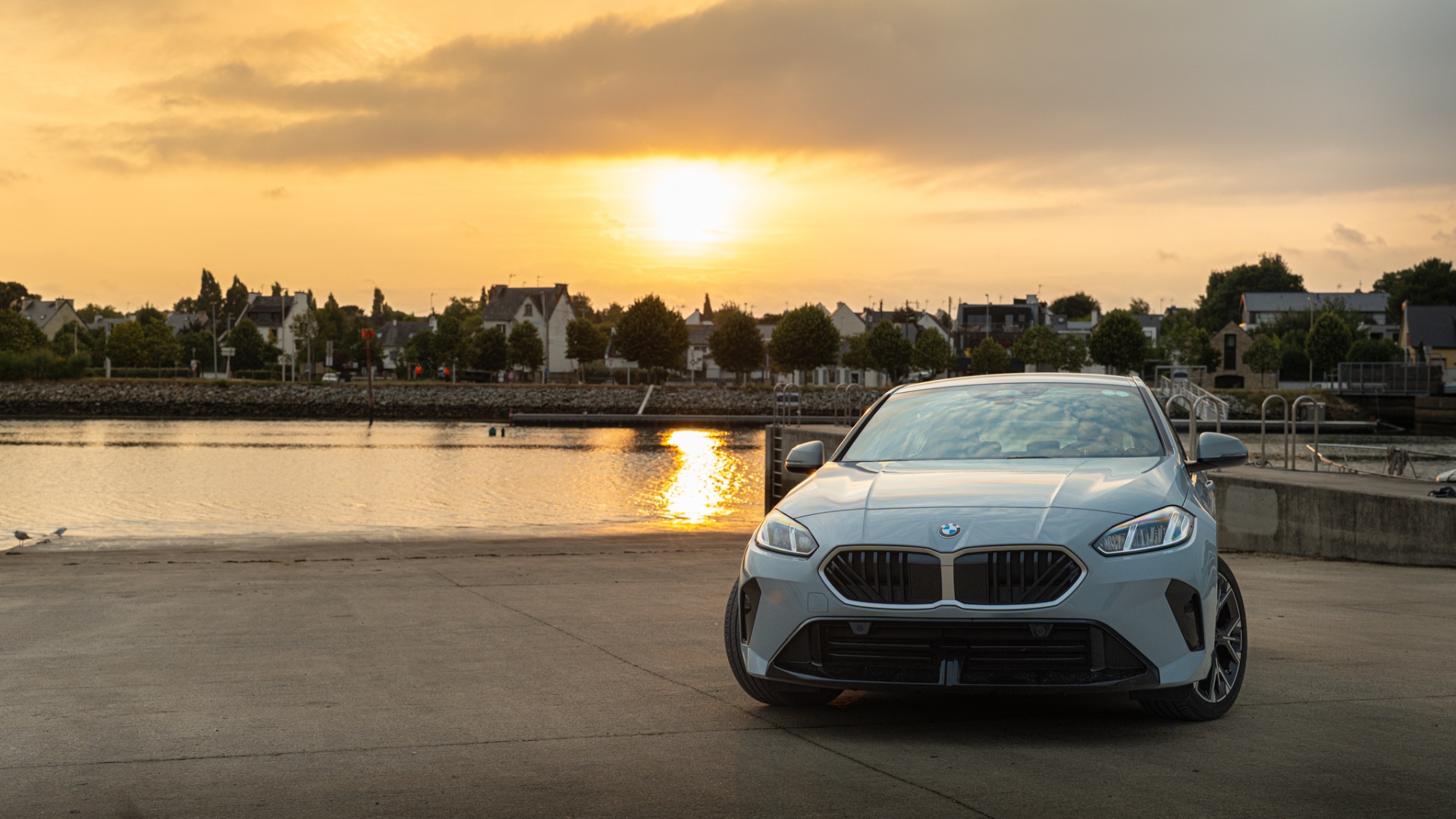 BMW Série 1 face avant devant le port au coucher du soleil