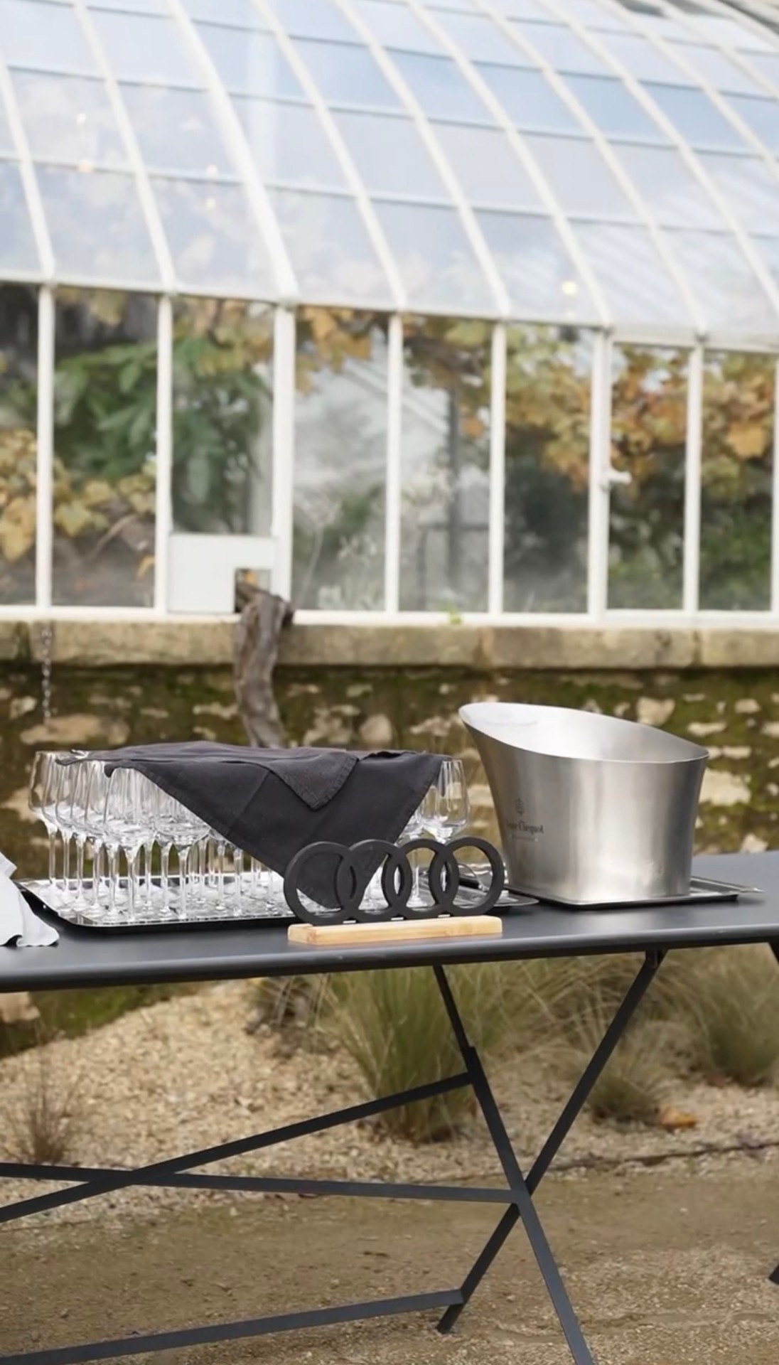 Table dressée avec flûtes et seau Veuve Clicquot devant une serre