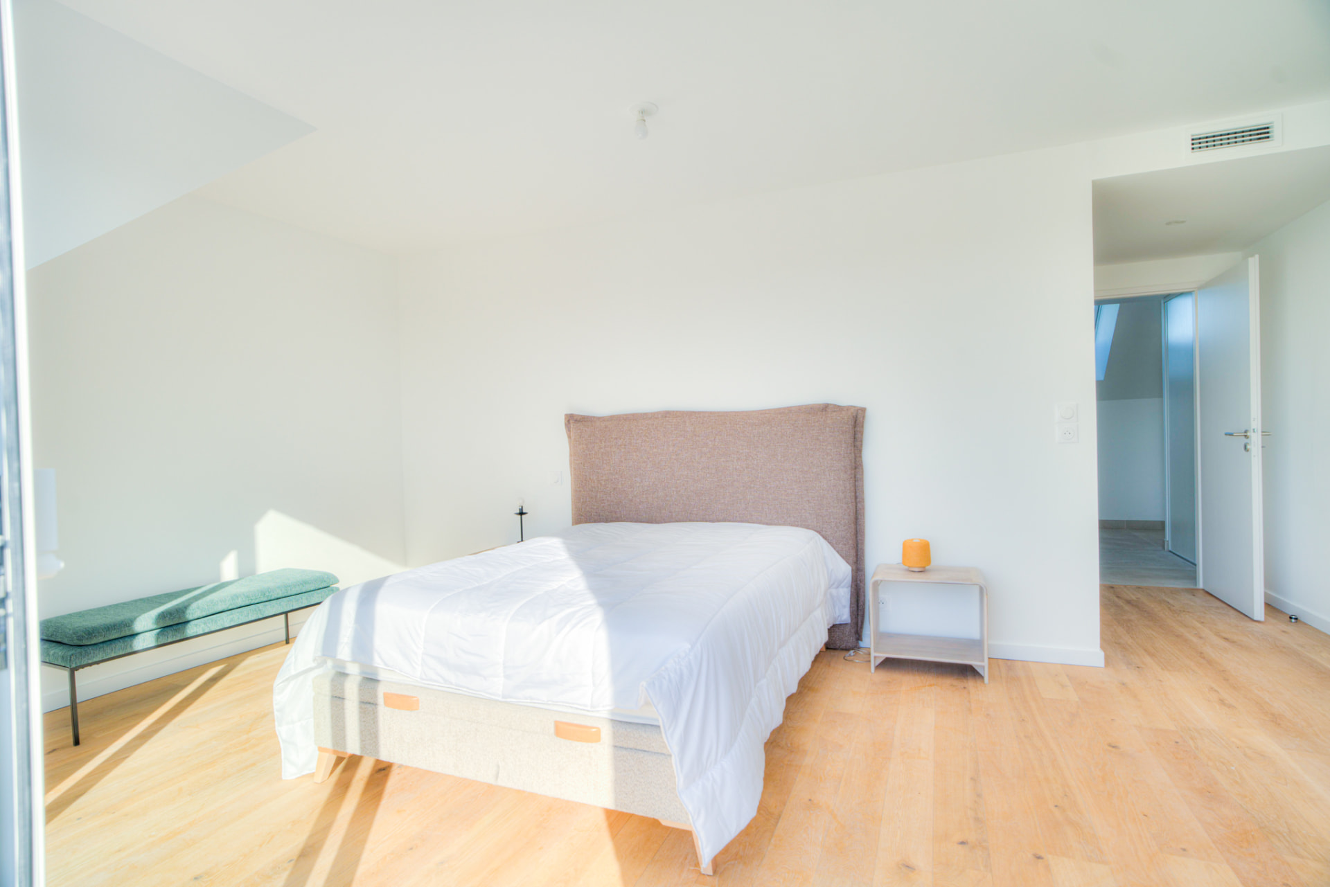 Chambre avec lit double, tête de lit beige et chevet